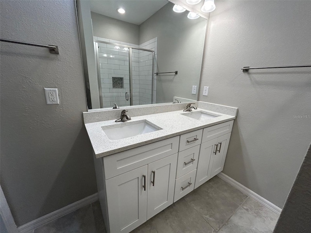 bathroom with a shower stall, double vanity, baseboards, and a sink