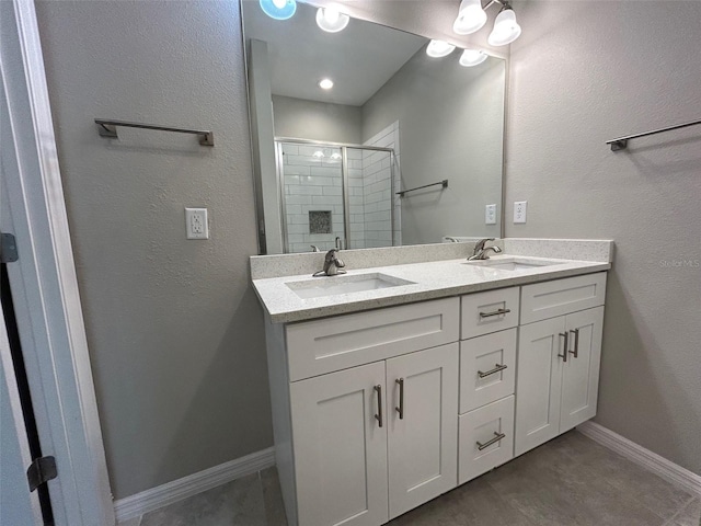 full bathroom with a shower stall, double vanity, baseboards, and a sink