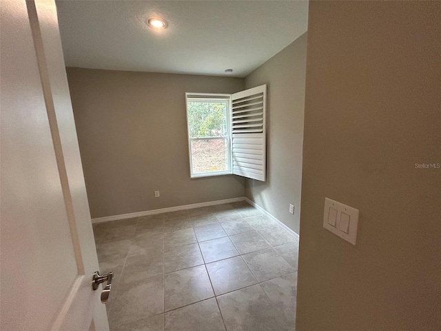 spare room featuring light tile patterned flooring and baseboards