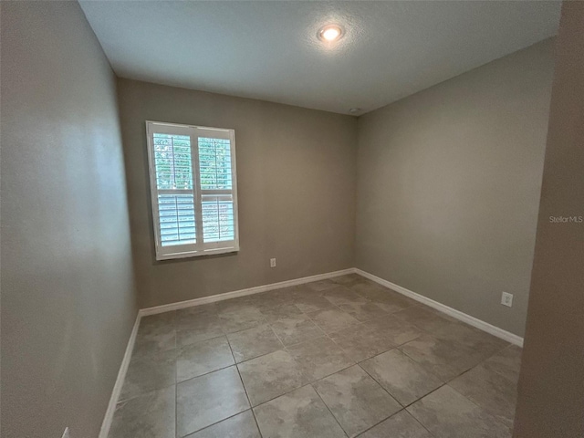 unfurnished room with light tile patterned flooring and baseboards