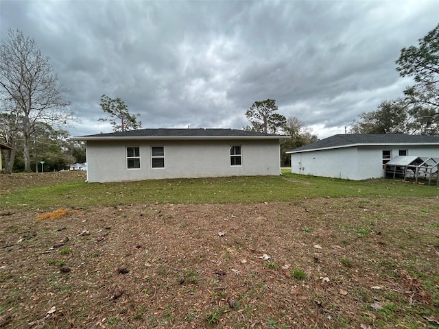 rear view of house with a lawn and stucco siding