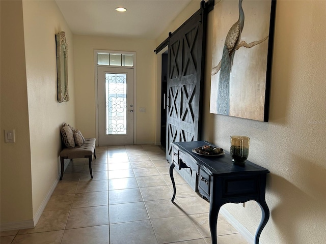 foyer entrance featuring light tile patterned floors, baseboards, and a barn door