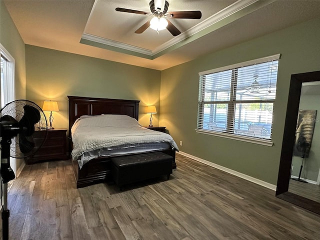 bedroom with a tray ceiling, baseboards, wood finished floors, and ornamental molding