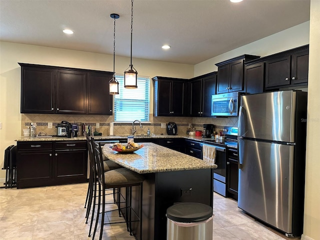 kitchen featuring a sink, light stone counters, a kitchen breakfast bar, stainless steel appliances, and decorative backsplash