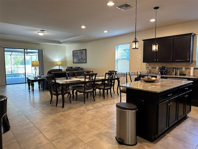 kitchen with light stone counters, visible vents, a healthy amount of sunlight, and decorative backsplash