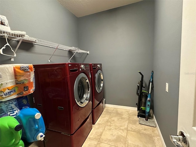 laundry area with a textured ceiling, laundry area, baseboards, and washer and clothes dryer