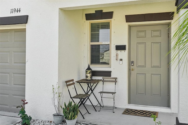 entrance to property with stucco siding and a garage