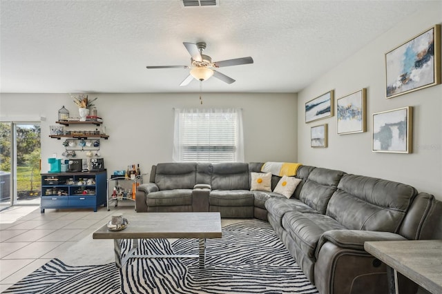 living area with light tile patterned floors, visible vents, a textured ceiling, and a ceiling fan