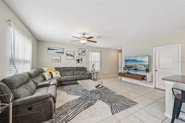 living room featuring light tile patterned flooring, baseboards, visible vents, and ceiling fan