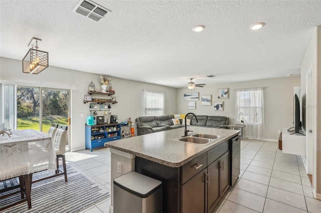 kitchen with visible vents, a sink, dark brown cabinetry, dishwasher, and open floor plan