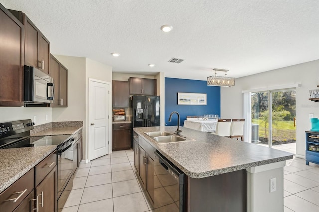 kitchen with black appliances, a center island with sink, a sink, light tile patterned floors, and dark brown cabinets