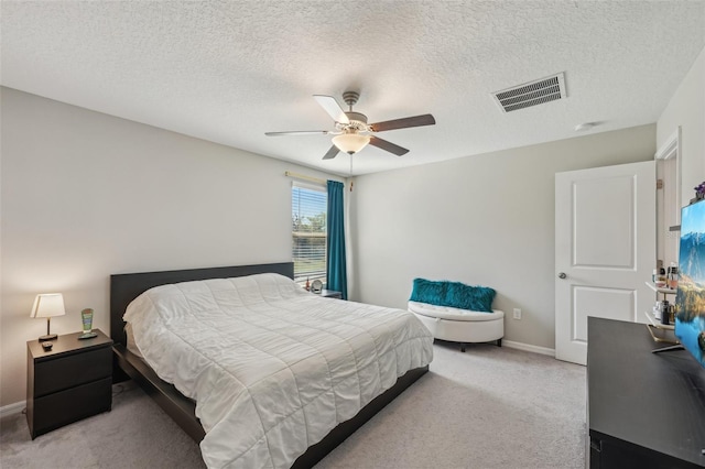 bedroom with a ceiling fan, baseboards, visible vents, a textured ceiling, and light carpet