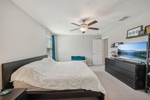 carpeted bedroom featuring visible vents, a textured ceiling, and a ceiling fan