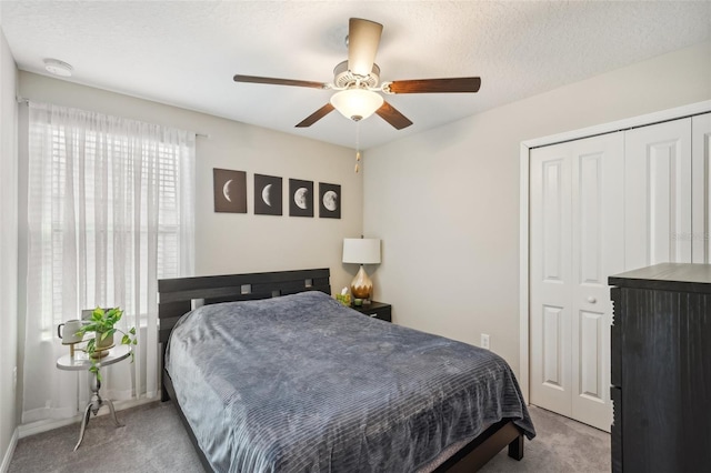 bedroom with a closet, a textured ceiling, a ceiling fan, and carpet floors