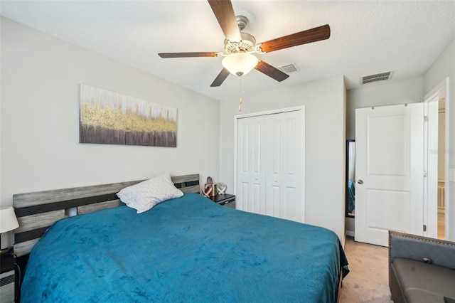 bedroom with a closet, visible vents, light colored carpet, and a ceiling fan