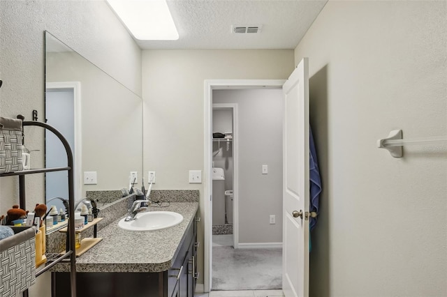 bathroom featuring visible vents, baseboards, a textured ceiling, and vanity