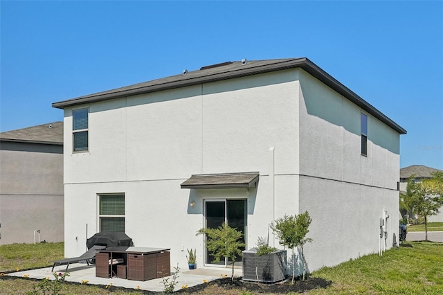 rear view of house with a patio area, stucco siding, and a lawn