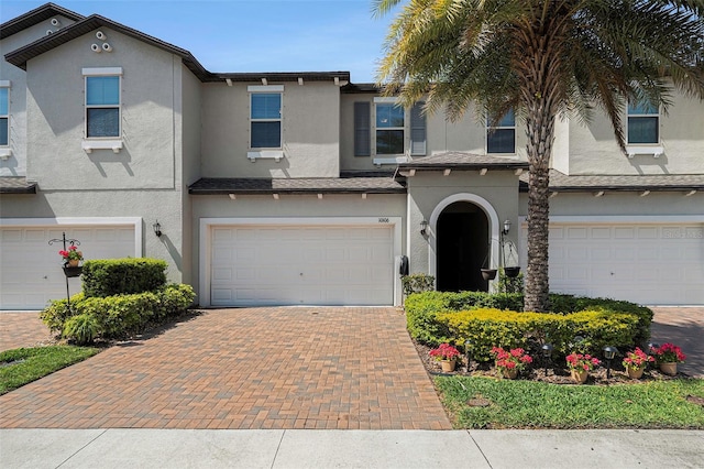 view of front of property featuring stucco siding, an attached garage, and decorative driveway