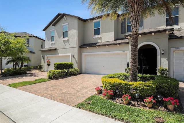 view of front of property featuring stucco siding, decorative driveway, and a garage