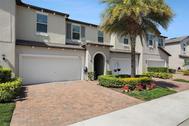 view of front of home featuring decorative driveway, an attached garage, and stucco siding