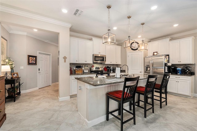 kitchen featuring a kitchen bar, visible vents, a kitchen island with sink, white cabinetry, and appliances with stainless steel finishes