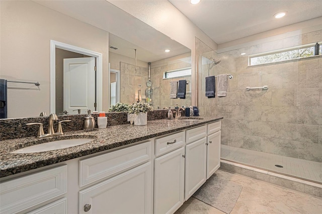 bathroom featuring double vanity, a walk in shower, and a sink