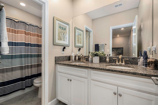 bathroom featuring tile patterned flooring, double vanity, toilet, and a sink