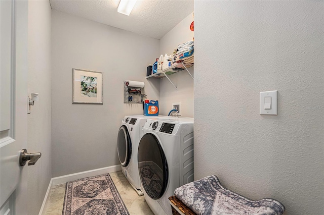 washroom featuring baseboards, washer and clothes dryer, laundry area, a textured wall, and a textured ceiling