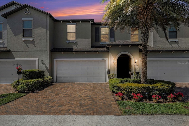 view of front facade with decorative driveway, a garage, and stucco siding