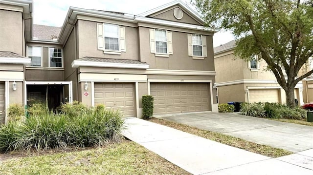 townhome / multi-family property featuring stucco siding, driveway, and a garage