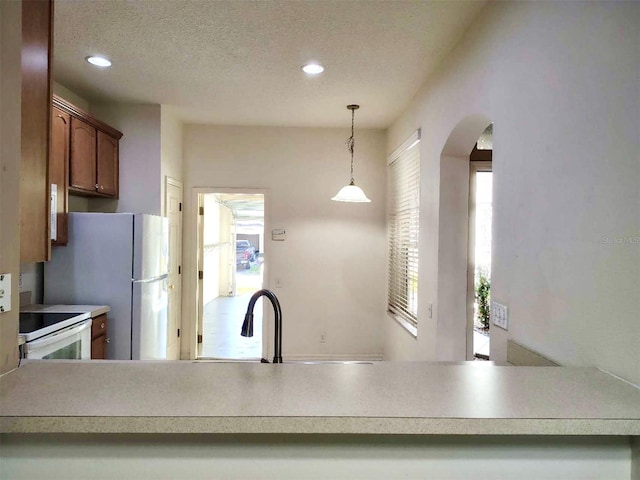 kitchen with decorative light fixtures, recessed lighting, arched walkways, white appliances, and a textured ceiling