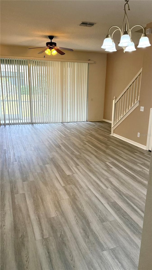 unfurnished living room with visible vents, wood finished floors, and ceiling fan with notable chandelier