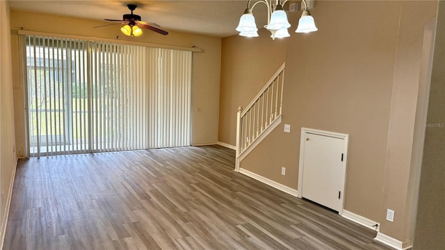 interior space featuring stairway, baseboards, wood finished floors, and ceiling fan with notable chandelier