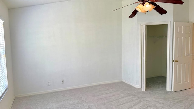 unfurnished bedroom with a walk in closet, baseboards, ceiling fan, light colored carpet, and a closet