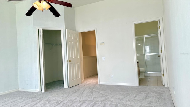 unfurnished bedroom with baseboards, a closet, a walk in closet, carpet flooring, and connected bathroom