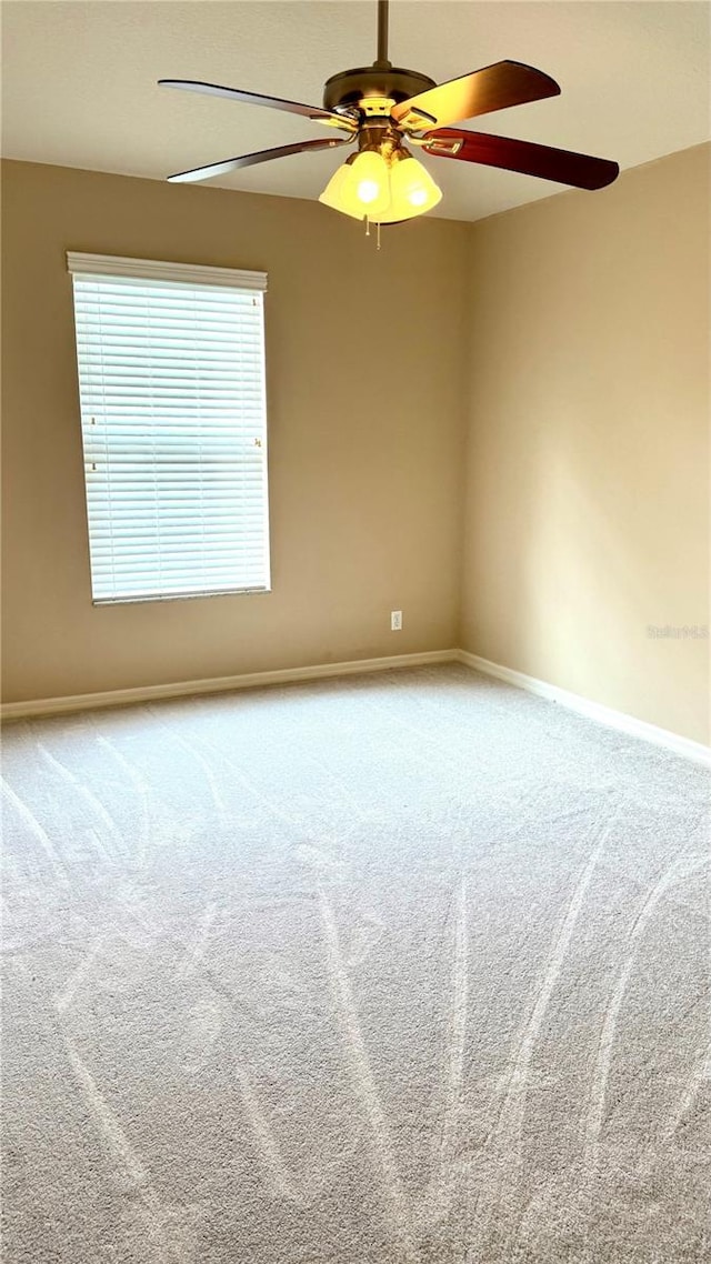 unfurnished room with carpet flooring, baseboards, and a ceiling fan