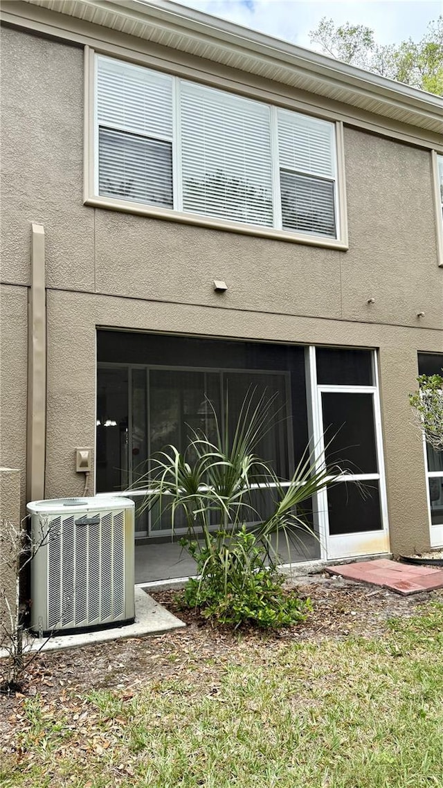 rear view of property featuring stucco siding and central AC unit