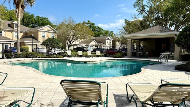 community pool with a patio area, a residential view, and fence