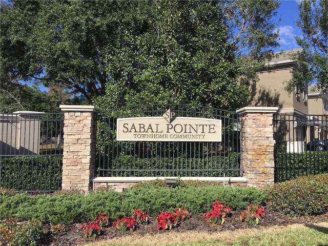 community / neighborhood sign with a gate and fence