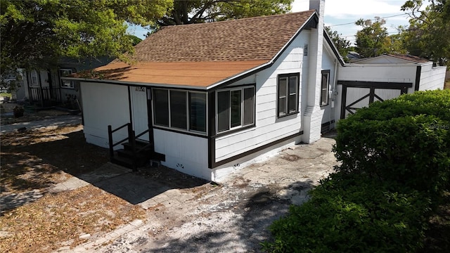 view of side of property featuring a shingled roof, a chimney, and entry steps