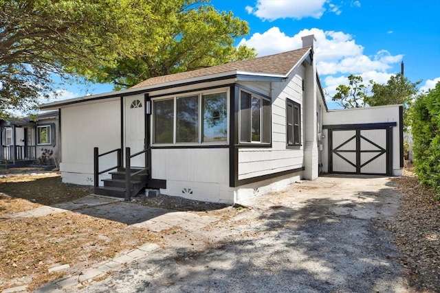 view of front of property with a shingled roof, entry steps, a chimney, crawl space, and driveway