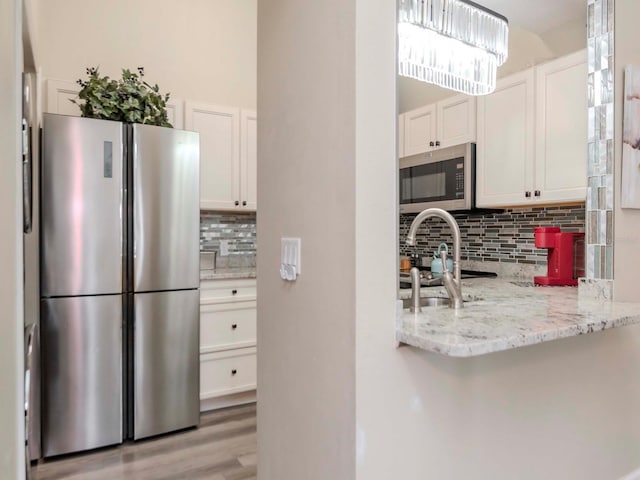 5100 Burchette Rd Unit 500, Tampa, FL 33647 - kitchen with stainless steel appliances, light wood-style flooring, white cabinetry, and tasteful backsplash