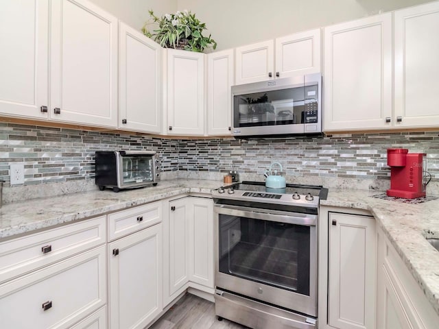 5100 Burchette Rd Unit 500, Tampa, FL 33647 - kitchen featuring white cabinets, appliances with stainless steel finishes, a toaster, and decorative backsplash