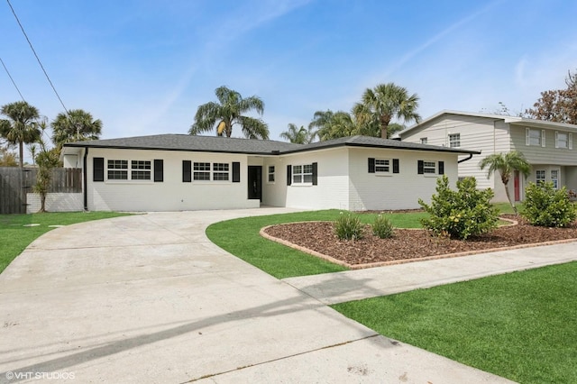 view of front of property with curved driveway, a front yard, and fence