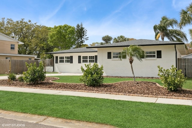 ranch-style home featuring brick siding, a front yard, and fence