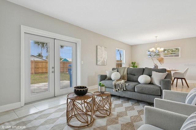 living area with light tile patterned flooring, a notable chandelier, french doors, and baseboards