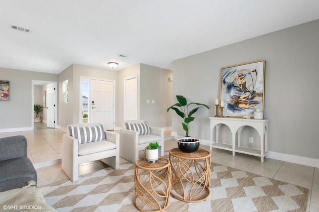 living room featuring light tile patterned floors, visible vents, and baseboards