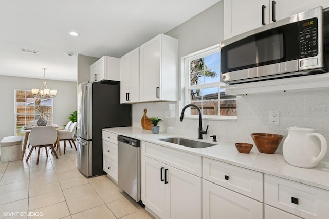 kitchen with visible vents, a notable chandelier, a sink, backsplash, and appliances with stainless steel finishes