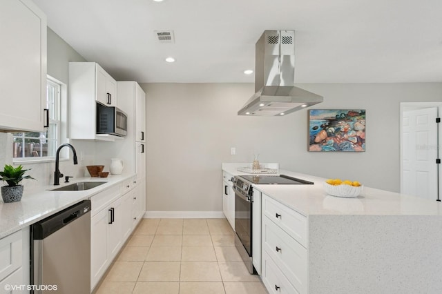 kitchen featuring visible vents, a peninsula, island exhaust hood, a sink, and appliances with stainless steel finishes