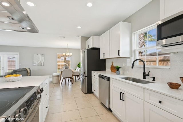 kitchen with a sink, white cabinetry, appliances with stainless steel finishes, light tile patterned floors, and decorative backsplash